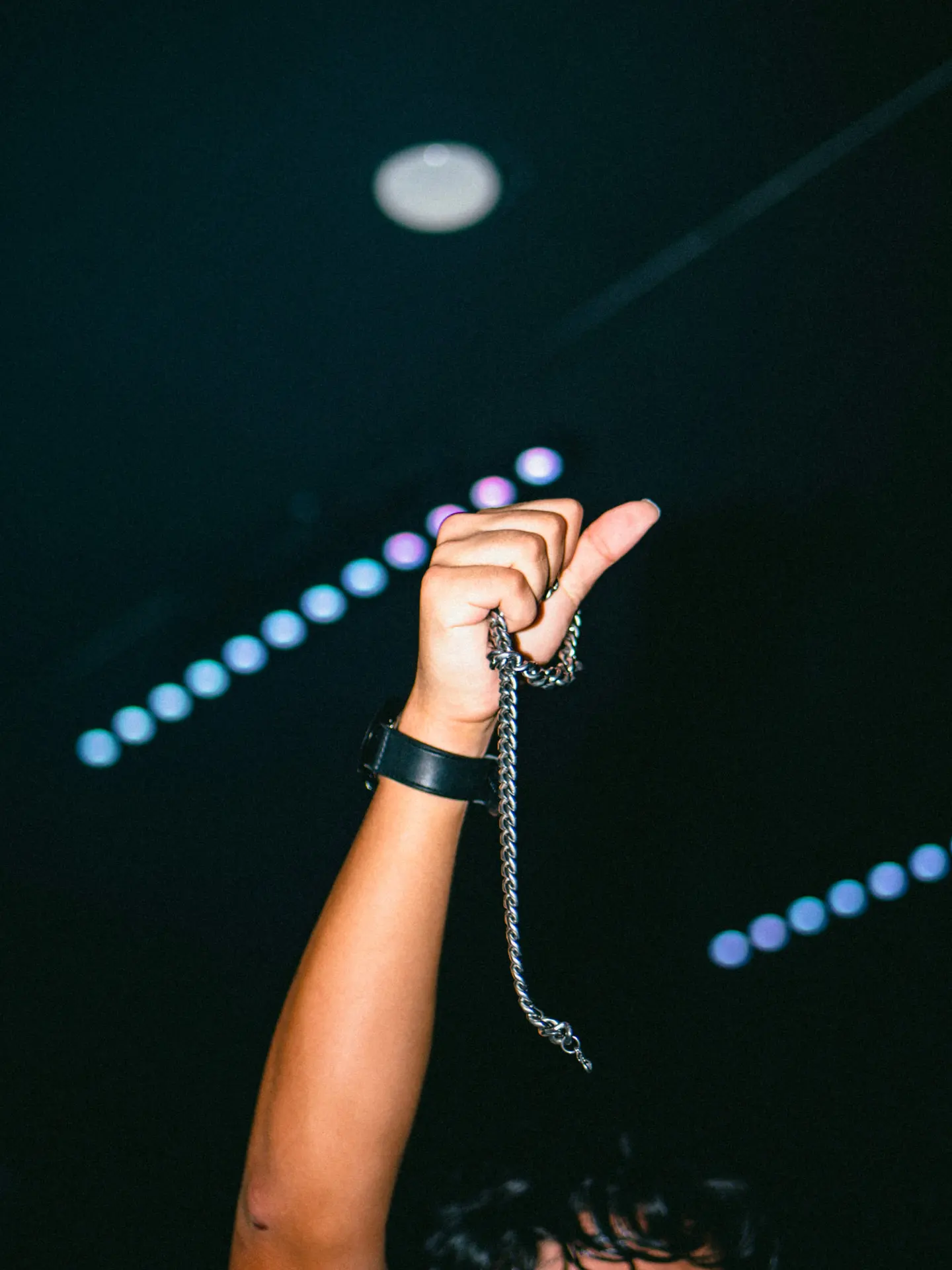 A raised fist clutching a silver chain above a crowd at a Gifted Summer Fest night show